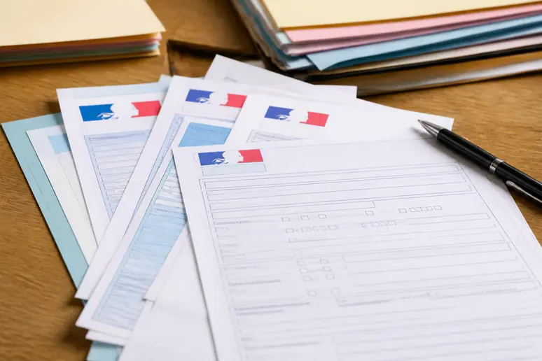 Documents administratifs pour les aides à la rénovation soigneusement disposés sur un bureau, prêts à être complétés.