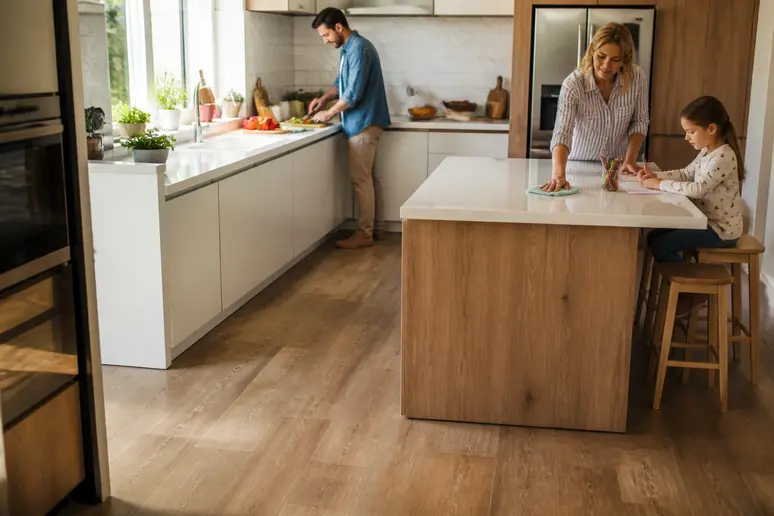Une famille française prépare un repas dans une cuisine lumineuse, le carrelage imitation bois résistant aux activités quotidiennes.