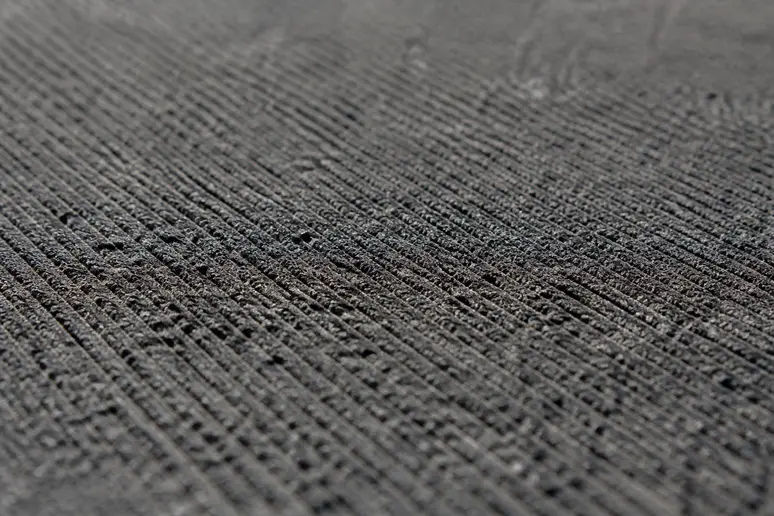 Surface texturée d'un carrelage gris foncé R10, révélant ses micro-rainures et reliefs.