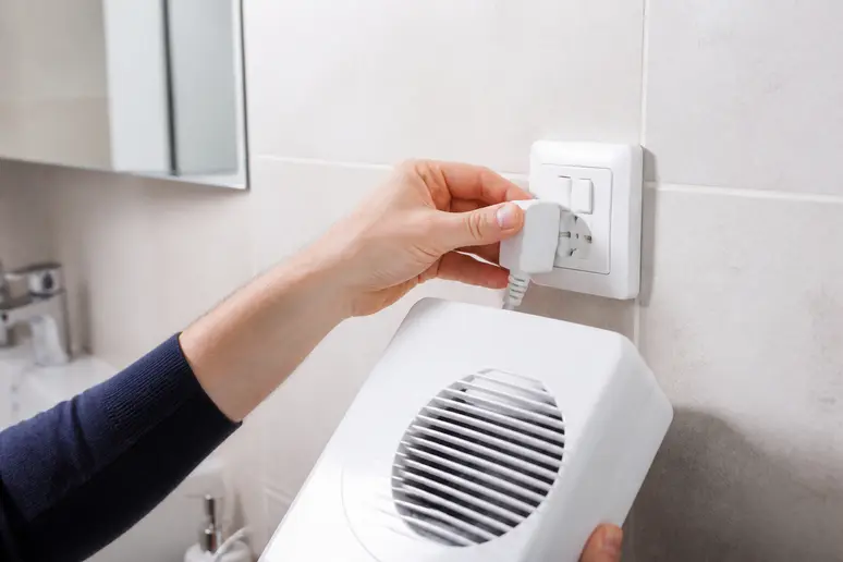 Mains raccordant un radiateur soufflant directement à une prise murale pour une sécurité optimale.