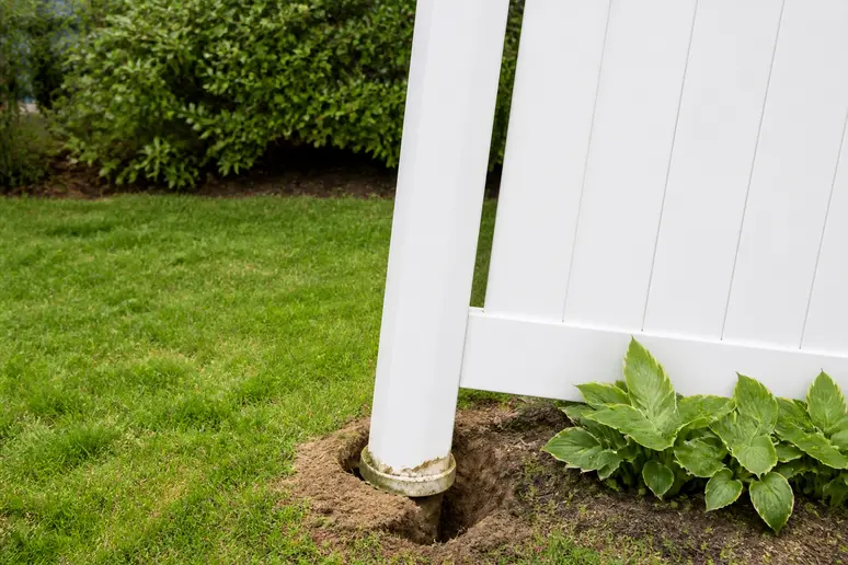 Un poteau de clôture en PVC visiblement instable et incliné