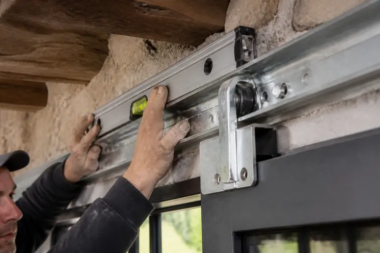 Gros plan sur un rail métallique de porte coulissante extérieure, solidement fixé, prêt à supporter une charge lourde.