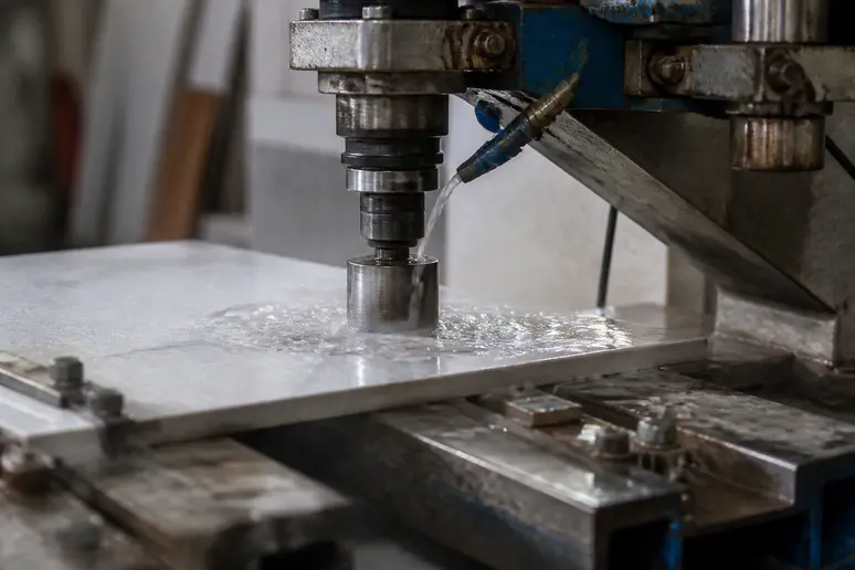 Forage à l'eau d'un carreau de grès cérame avec un trépan diamanté et un système de refroidissement.