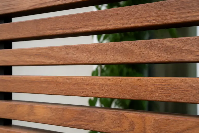 Gros plan sur la structure ajourée d'un panneau de tasseaux en bois, montrant les interstices.