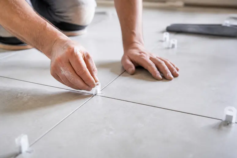 Pose de croisillons de carrelage entre des carreaux pour respecter l'espacement réglementaire